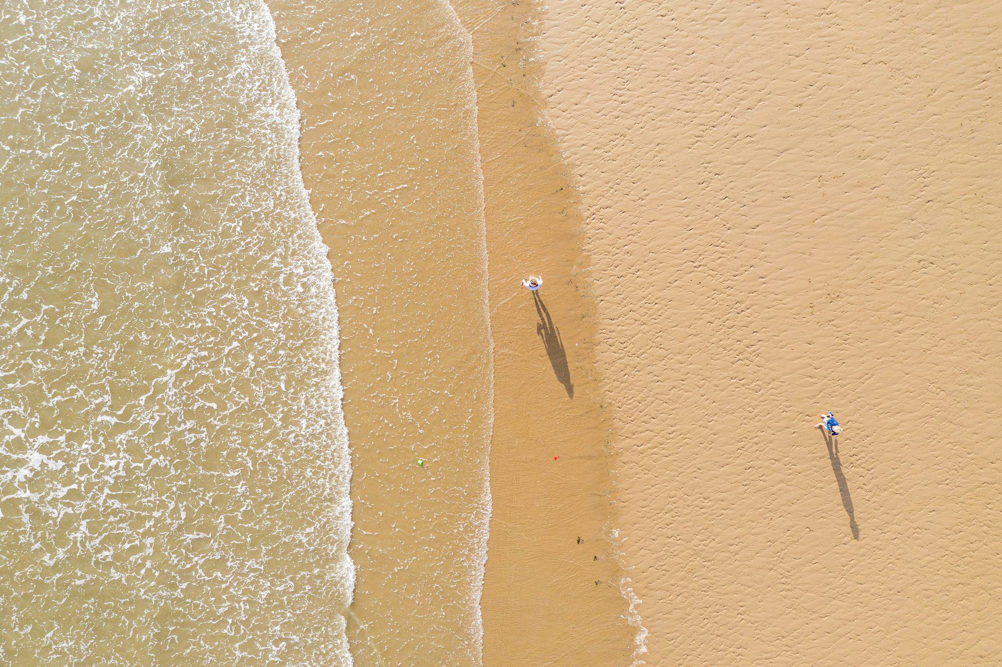 Two figures on the wet sand at Rest Bay, early morning