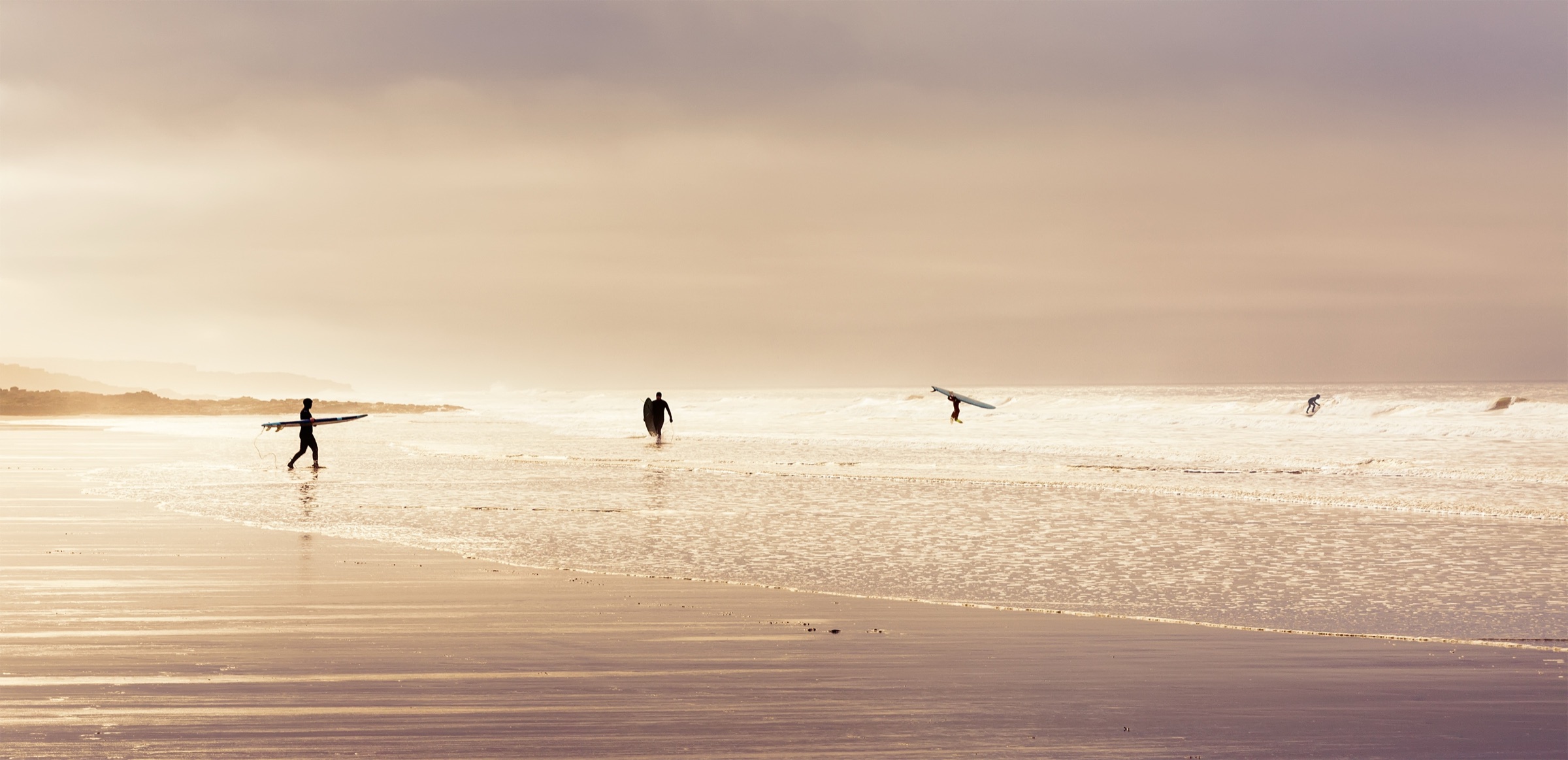 Surfers carrying boards down to the water