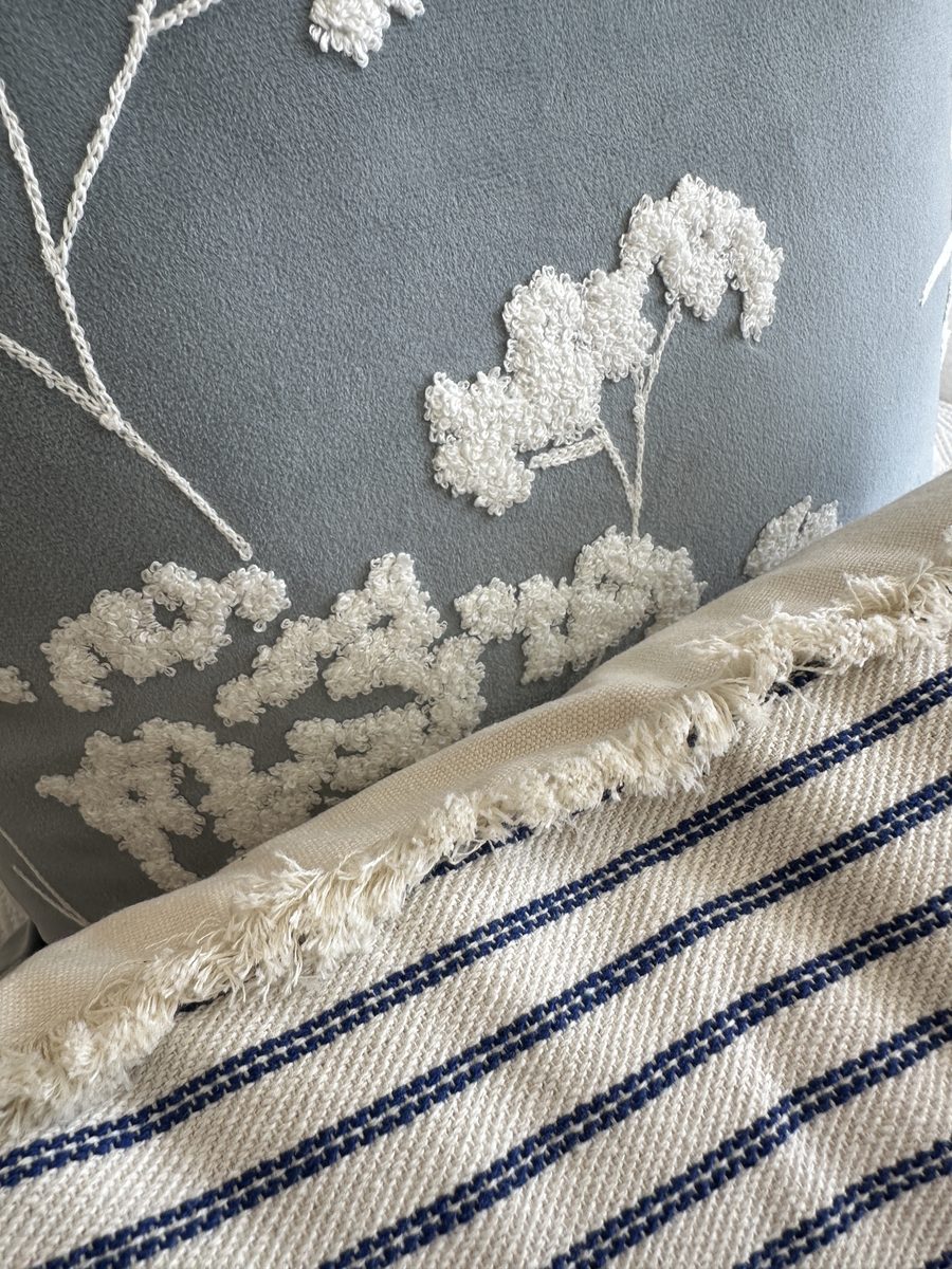 The Edmonton, an embroidered cushion beside a fringed throw