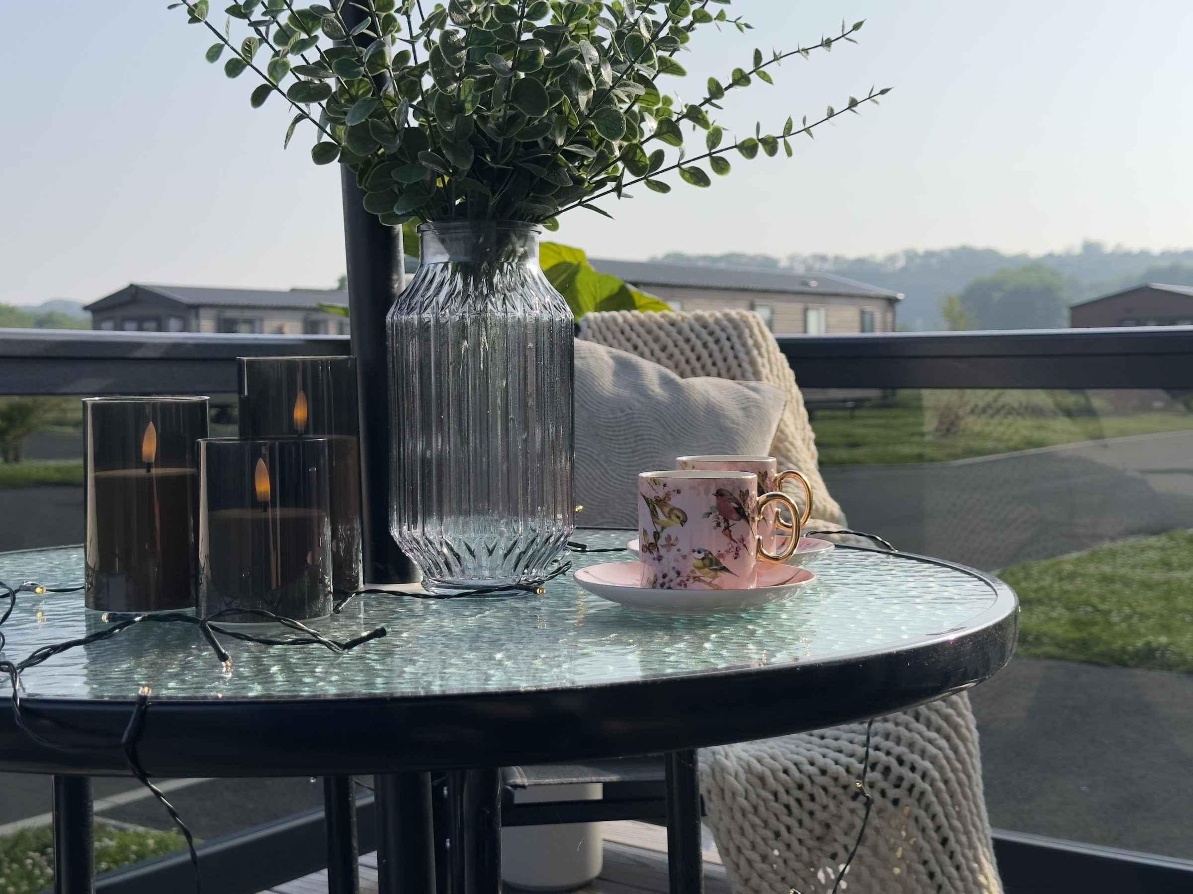 Coffee cups on a table on the decking of a lodge at Nottage Park Lodges